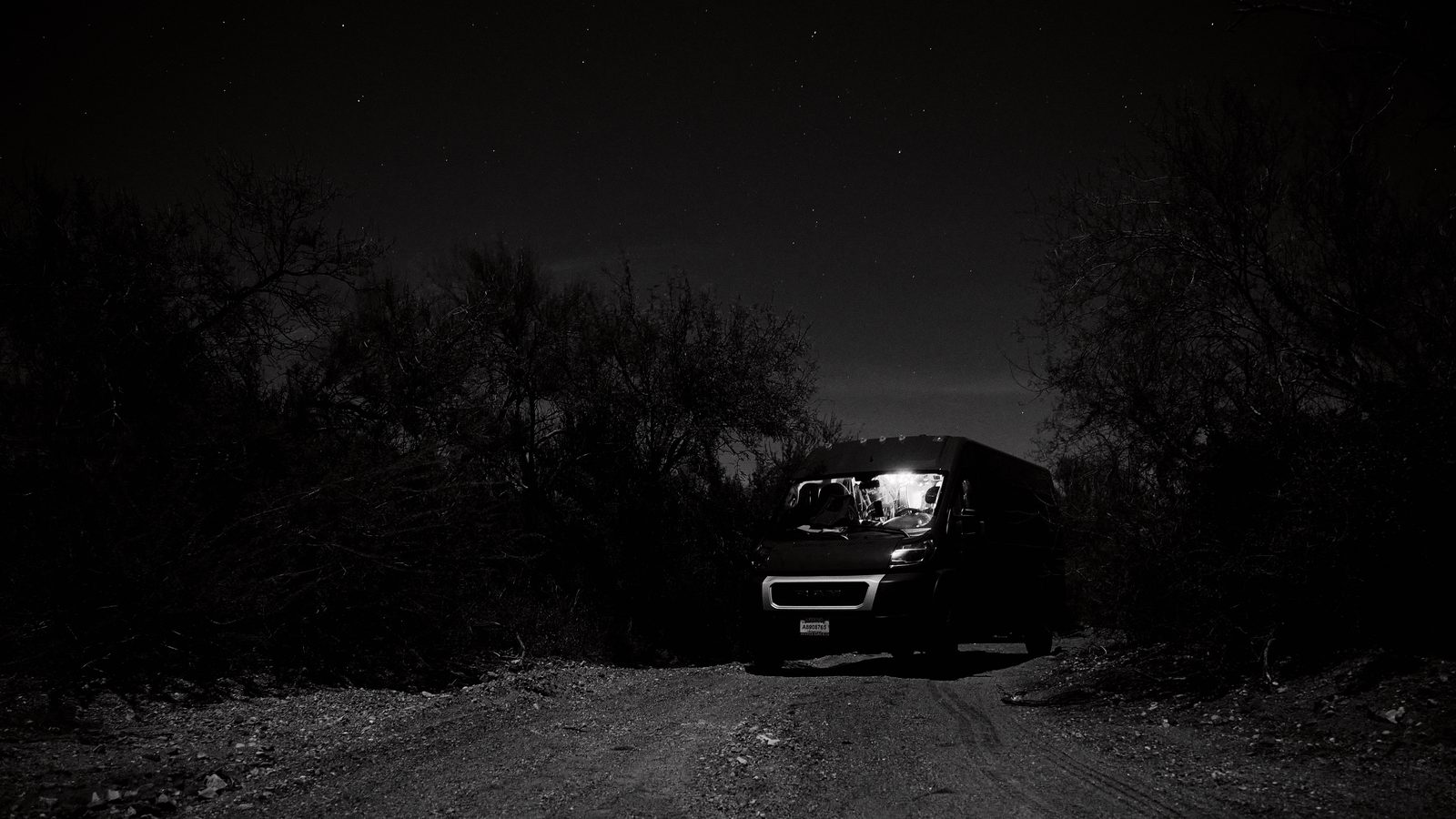Van parked on a dirt road under a star-filled sky